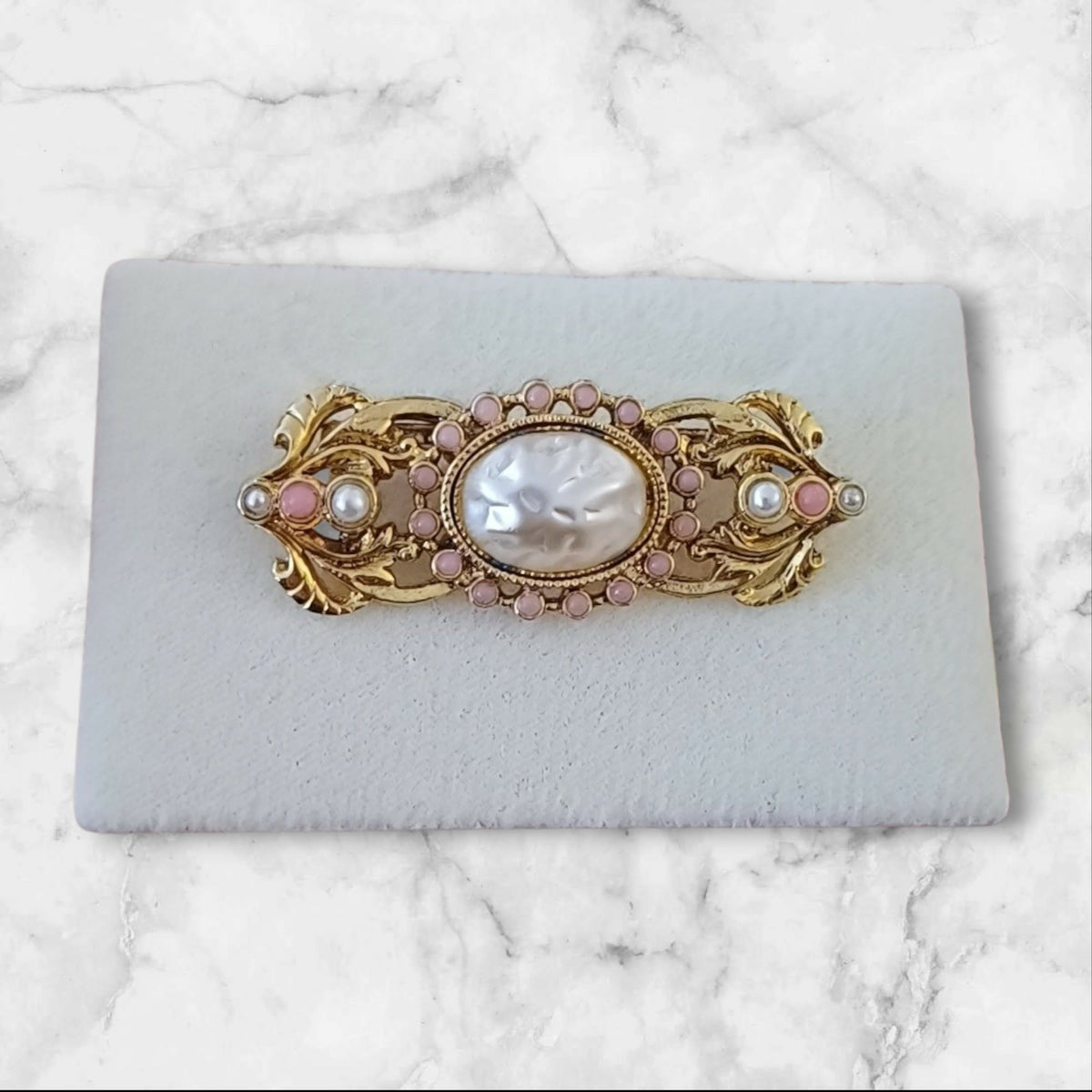 Gullfarget vintagebrosje med perlemor og rosa detaljer