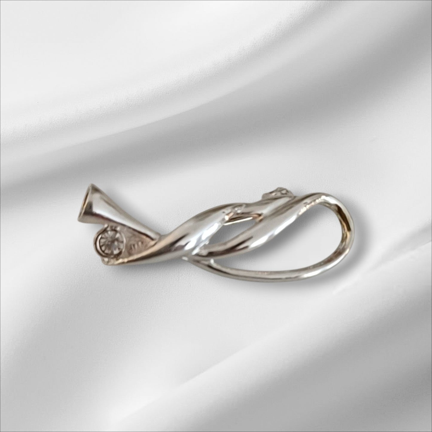 Sølvfarget brosje med sten, i elegant swirldesign