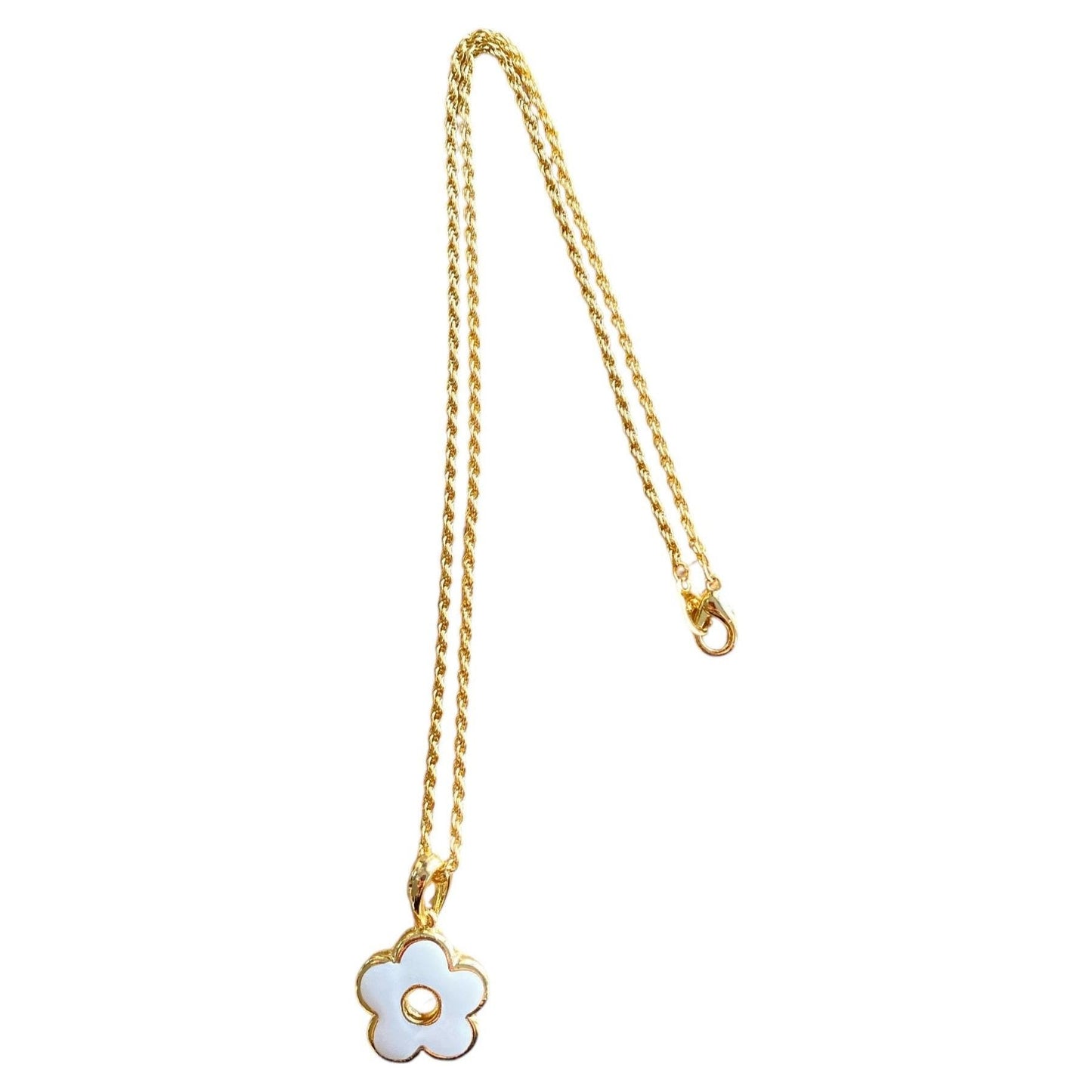 Emaljert smykke i gullfarget metall med hvit blomst