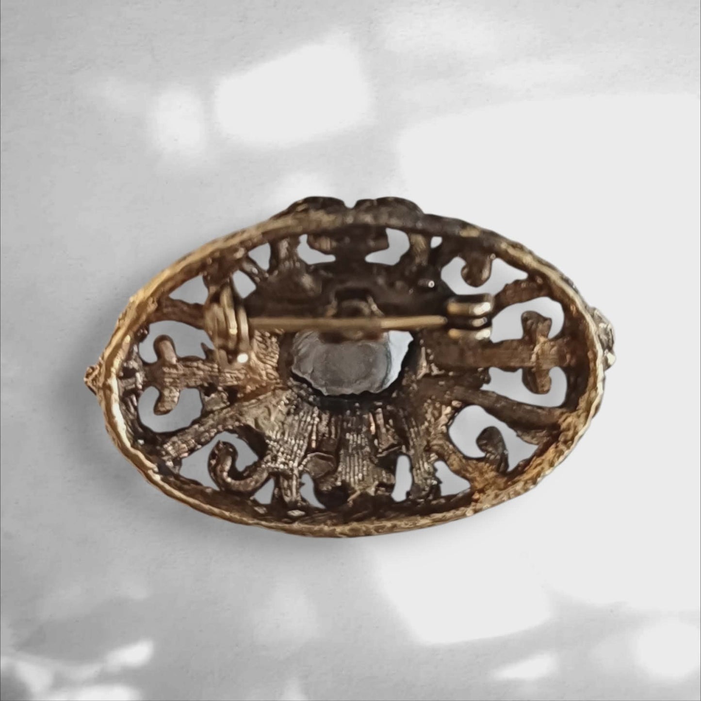 Vintagebrosje med blå sten og ornamentert design