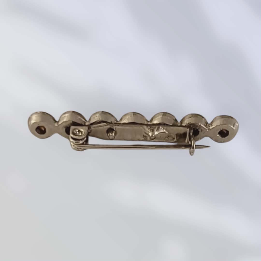 Vintagebrosje med hvite krystaller i rekke