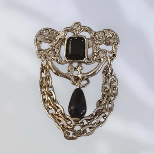 Vintagebrosje med sort sten og dekorative lenker