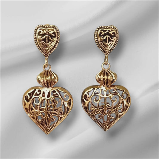 Øredobber i gullfarget metall med dekorative hjerter