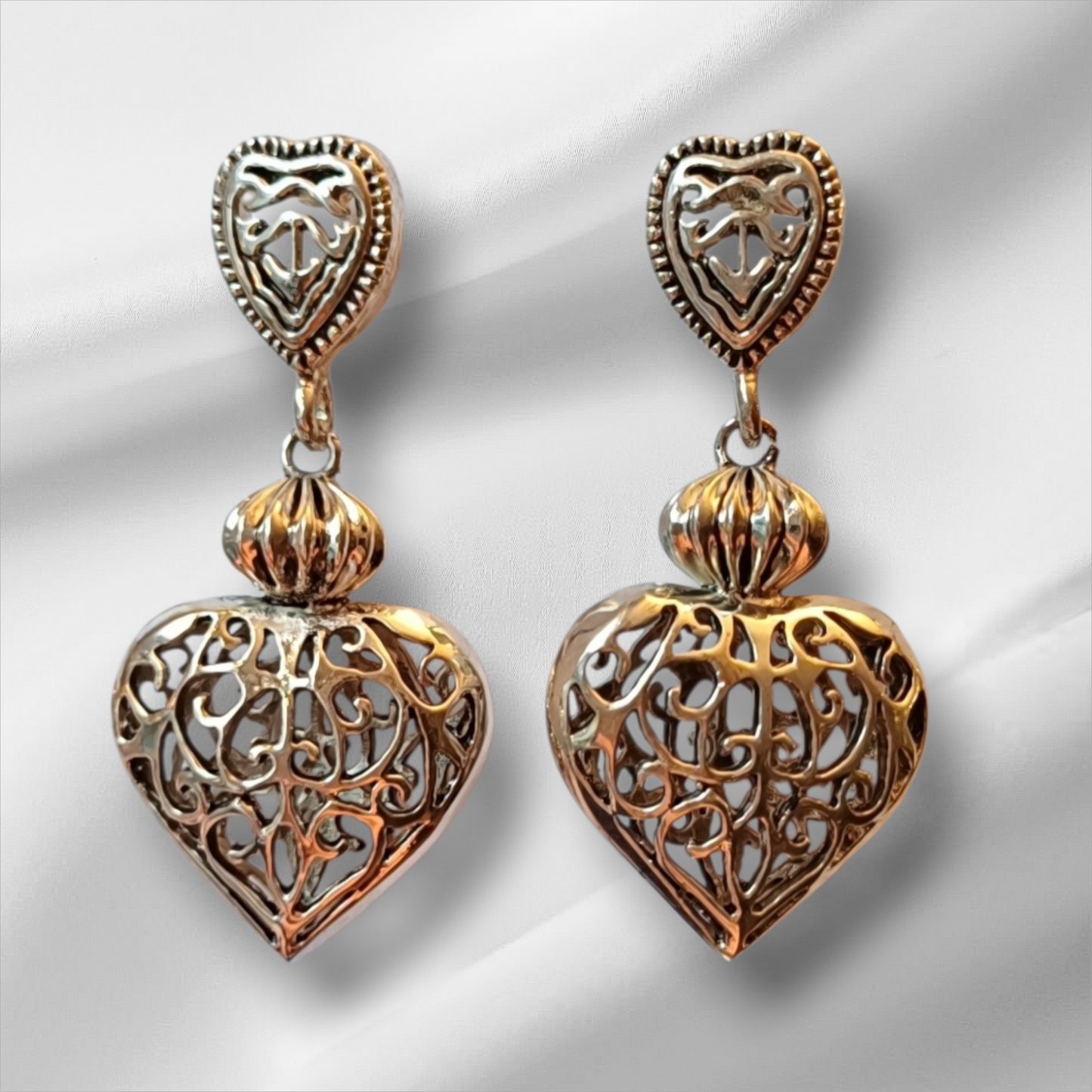 Øredobber i sølvfarget metall med dekorative hjerter