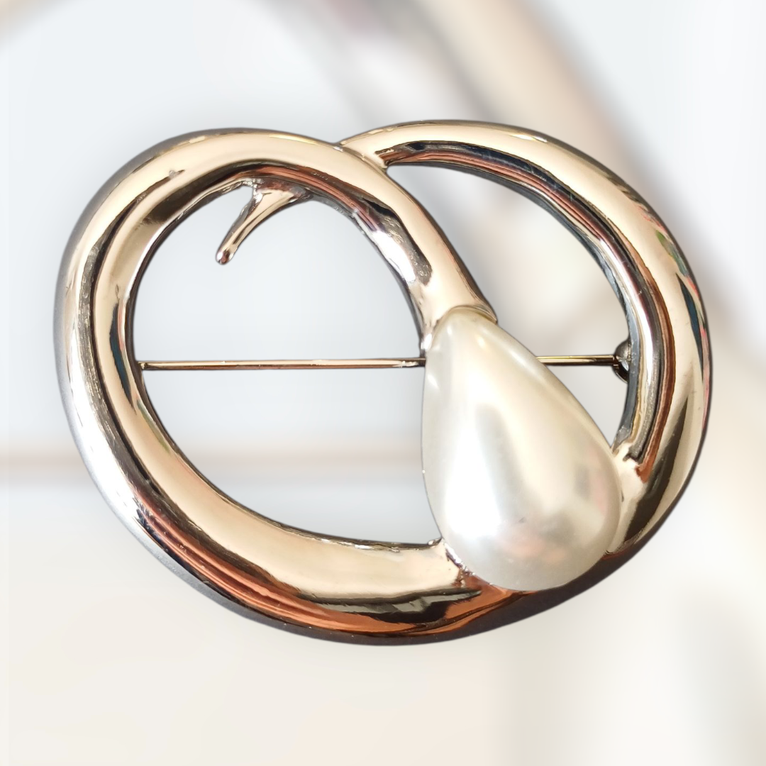 Stor sølvfarget brosje med dråpeformet perledetalj