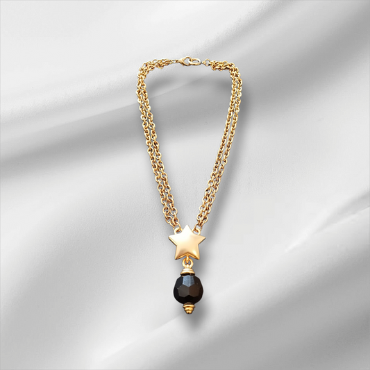 Gullfarget halskjede med stjerneanheng og sort fasettslipt perle